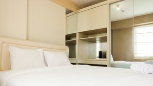 A hotel room with a large bed, a wardrobe, and a mirror. - Contemporary 2BR at Bassura City Apartment (Jakarta)