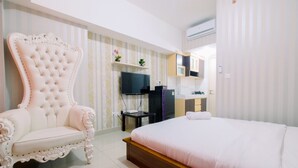 Un dormitorio con una cama grande, un sillón decorativo, un televisor y una mesita.