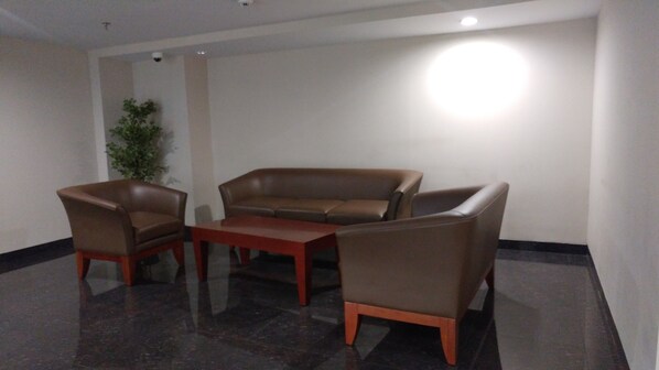 A room with a brown leather sofa, two armchairs, and a wooden coffee table.