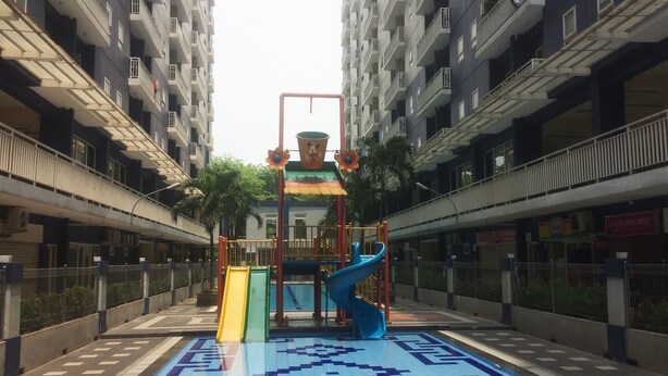Ein Spielplatz mit Rutschen und einer Kletterkonstruktion in städtischer Umgebung.