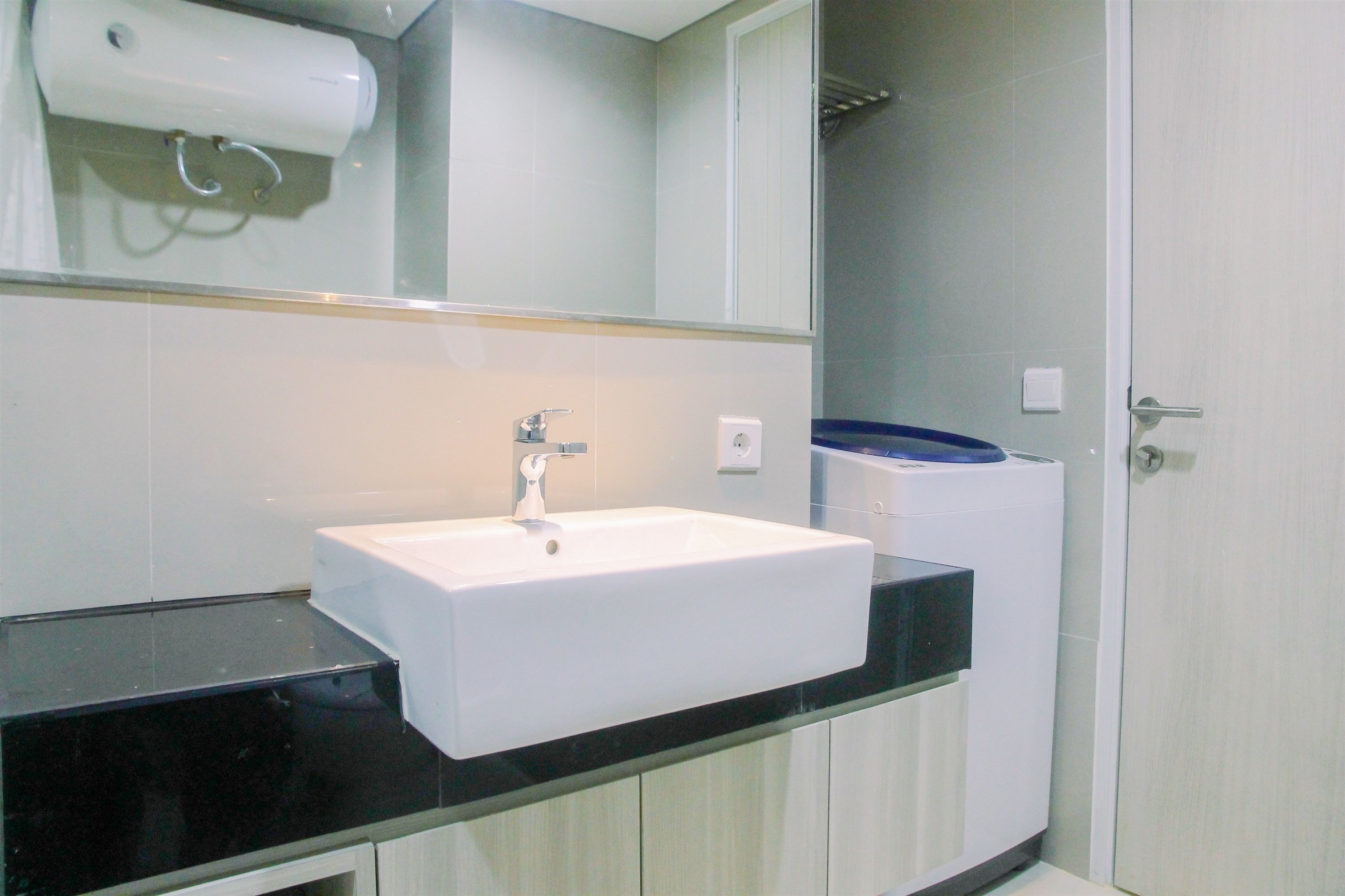 A bathroom with a white sink, black countertop, and a mirror above it.