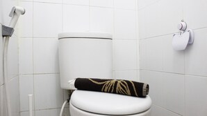 A white toilet with a towel on the seat and a toilet paper holder on the wall. - Minimalist 2BR Apartment at Gateway Ahmad Yani (Bandung)