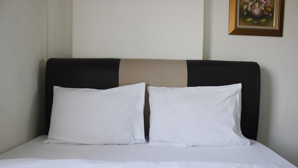 A neatly made bed with white bedding and a headboard with a beige accent. - Minimalist 2BR Apartment at Gateway Ahmad Yani (Bandung)