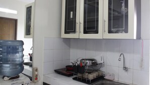 A kitchen with white cabinets, a water dispenser, a sink, and a dish rack. - Minimalist 2BR Apartment at Gateway Ahmad Yani (Bandung)