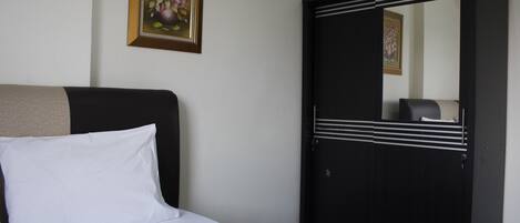 Een slaapkamer met een bed, een kledingkast en een lijst met bloemen op de muur.