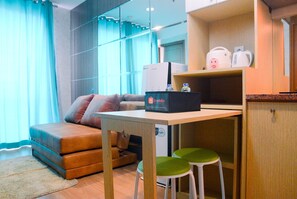 A compact living space with a sofa, a small table, and a kitchenette area. - Full Parquette 2BR @ Cinere Bellevue Apartment (Depok)