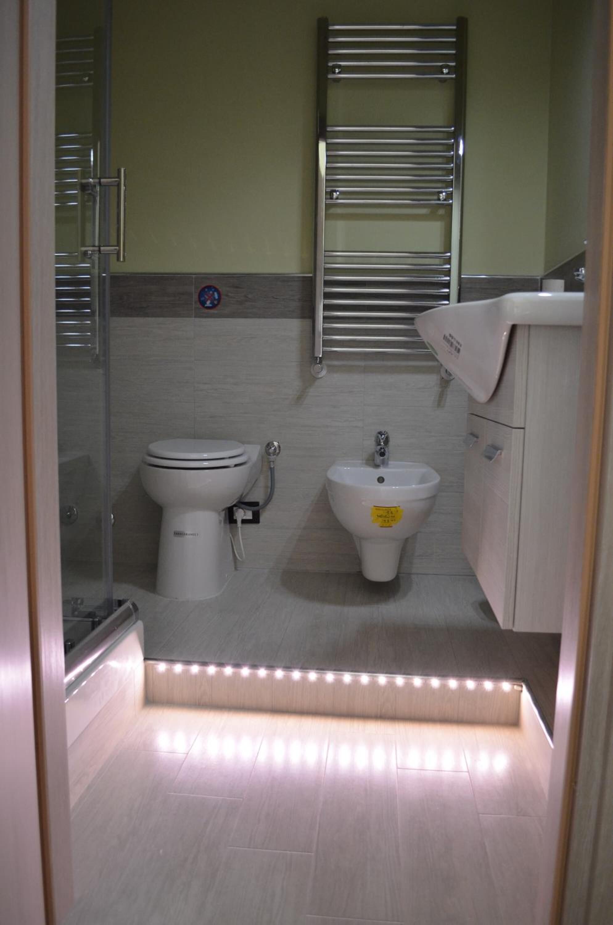 Ein modernes Badezimmer mit Toilette, Bidet und einer Duschkabine aus Glas.