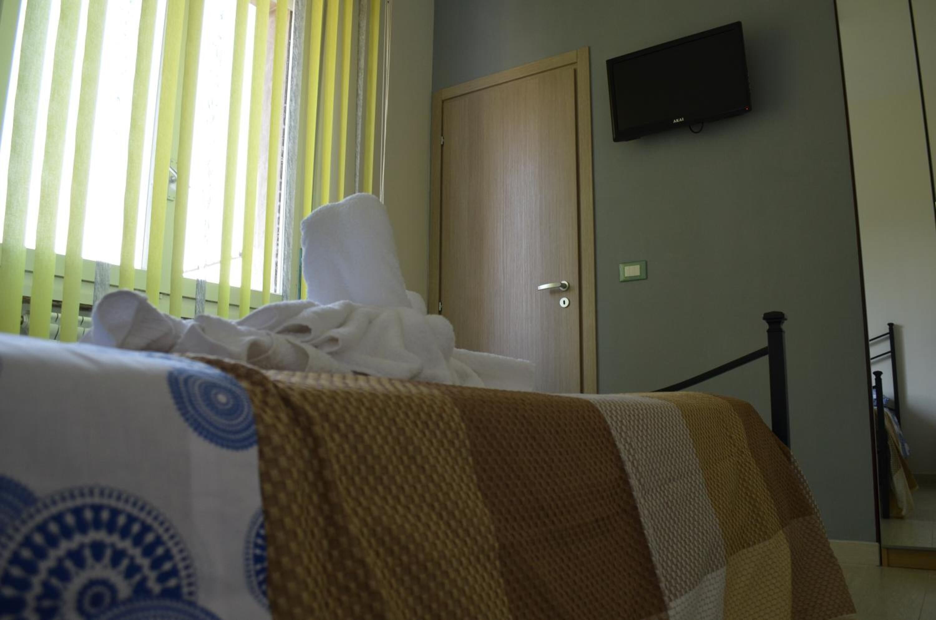 Una habitación de hotel con una cama, un televisor montado en la pared y una puerta.