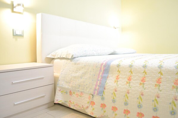 A bedroom with a bed, a nightstand, and a dresser.