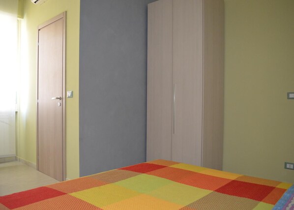 Una habitación con una cama, dos puertas y una pared con interruptor de luz.