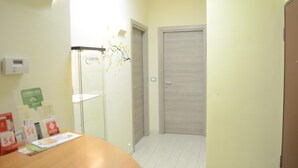 A hotel room with a wooden door, a small table with promotional materials, and a wall-mounted thermostat. - Casa Aurora B&B (Chieti)