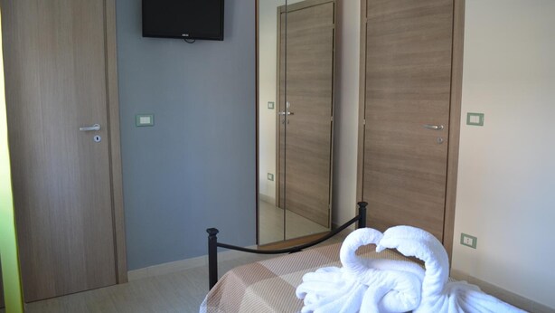 A hotel room with a bed, a TV mounted on the wall, and two wooden wardrobes. - Casa Aurora B&B (Chieti)