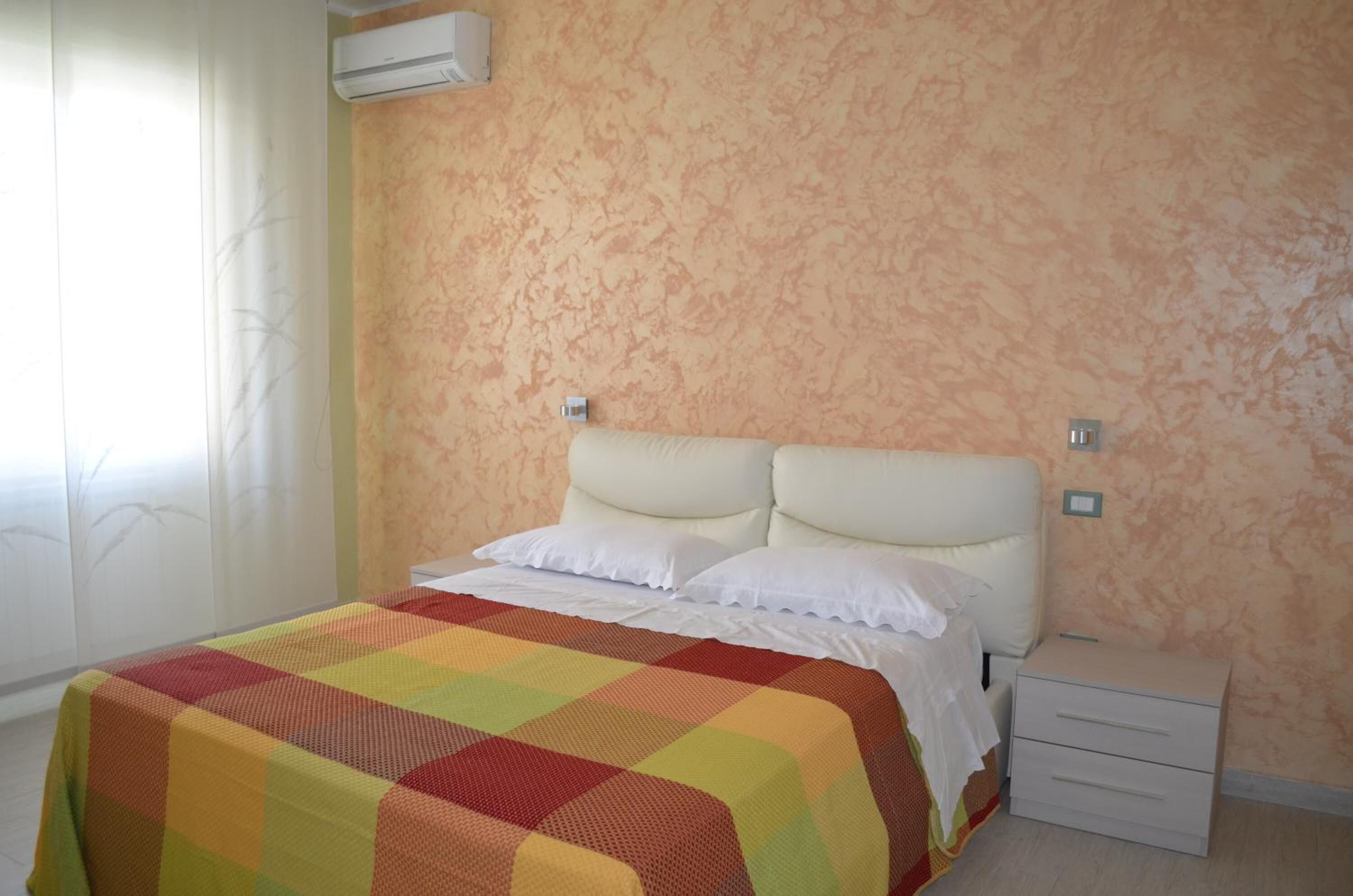 Une chambre à coucher avec un lit, une table de chevet et un appareil de climatisation fixé au mur.
