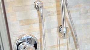 A shower with a chrome faucet and a flexible hose, a clear shower tray, and a tiled wall. - Casa Aurora B&B (Chieti)