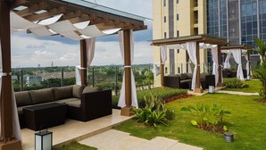 A rooftop patio with outdoor seating, a glass pergola, and a view of a cityscape. - Elegant 1BR Branz BSD Apartment near AEON Mall (Pagedangan)