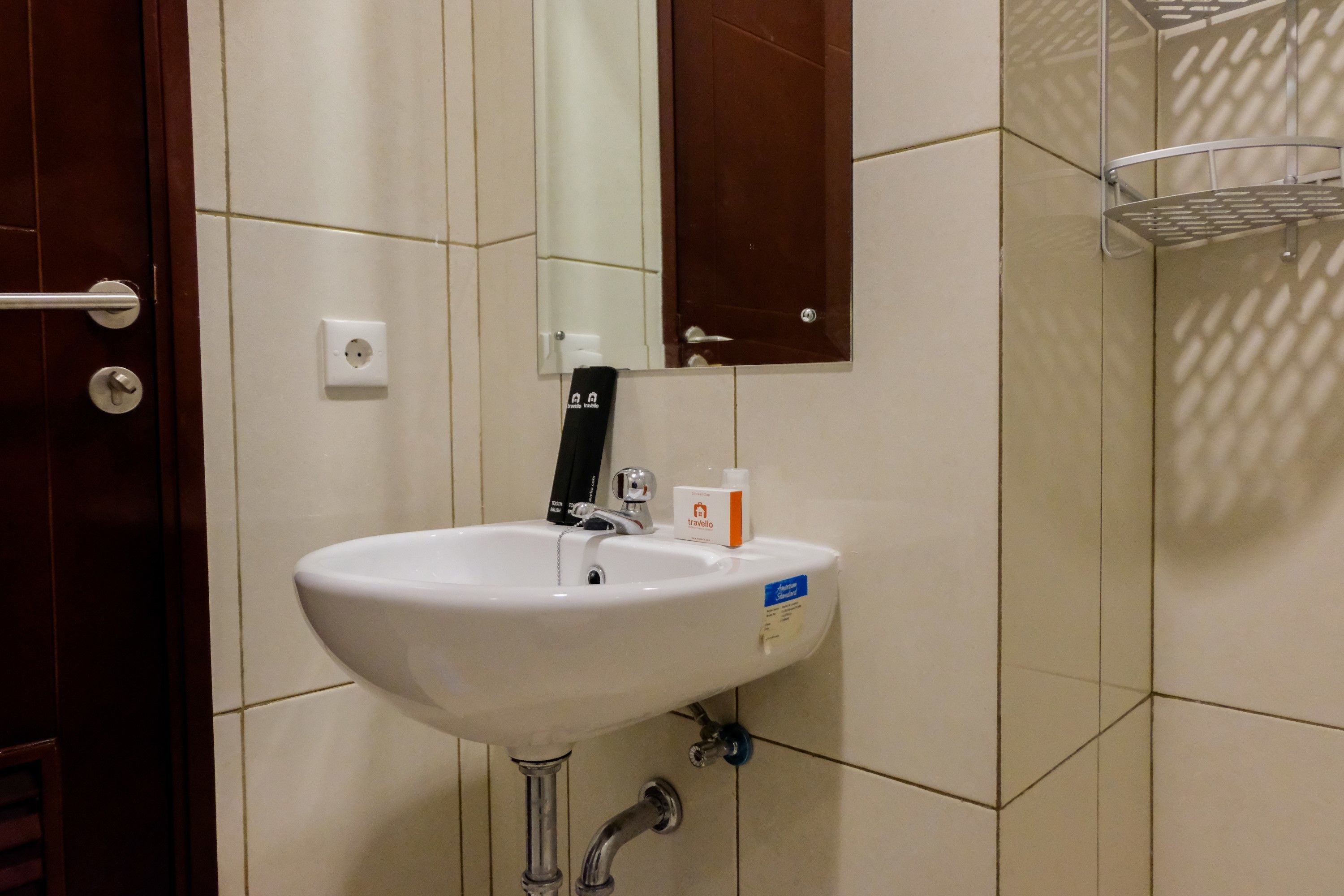 Ein Badezimmer mit weißem Waschbecken, einem Spiegel, einem Handtuchhalter und einer Tür.