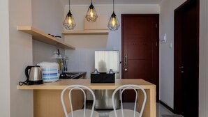 Eine moderne Küche mit einer Holzausziehtheke, zwei weißen Stühlen, einer Kaffeemaschine und hängenden Pendelleuchten.