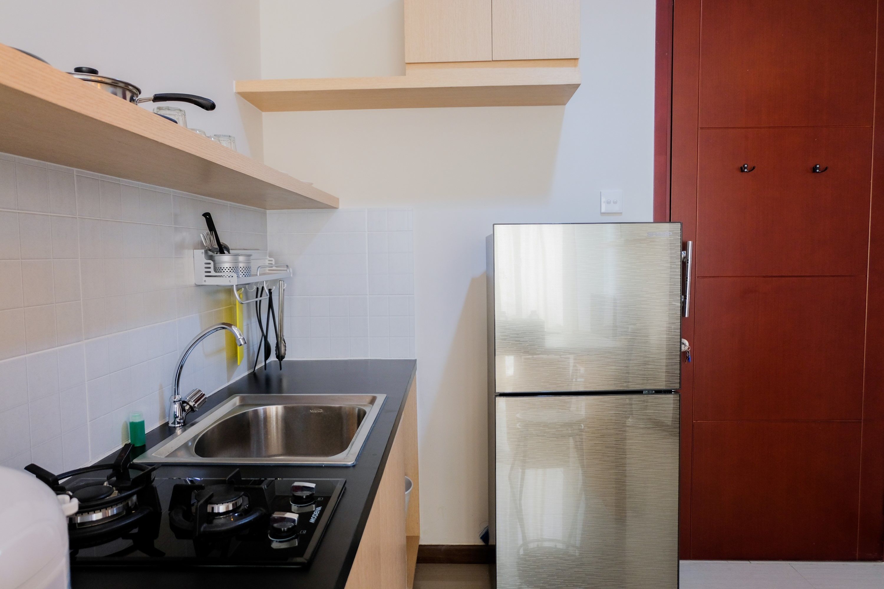 A compact kitchen with a stainless steel refrigerator, a gas stove, and a sink.