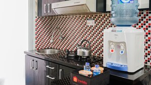 A kitchenette with a stove, sink, and water dispenser. - Comfy and Clean 2BR Green Pramuka Apartment (Jakarta)