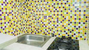 Una cocina con salpicadero de azulejos, un lavamanos de acero inoxidable y una estufa a gas.