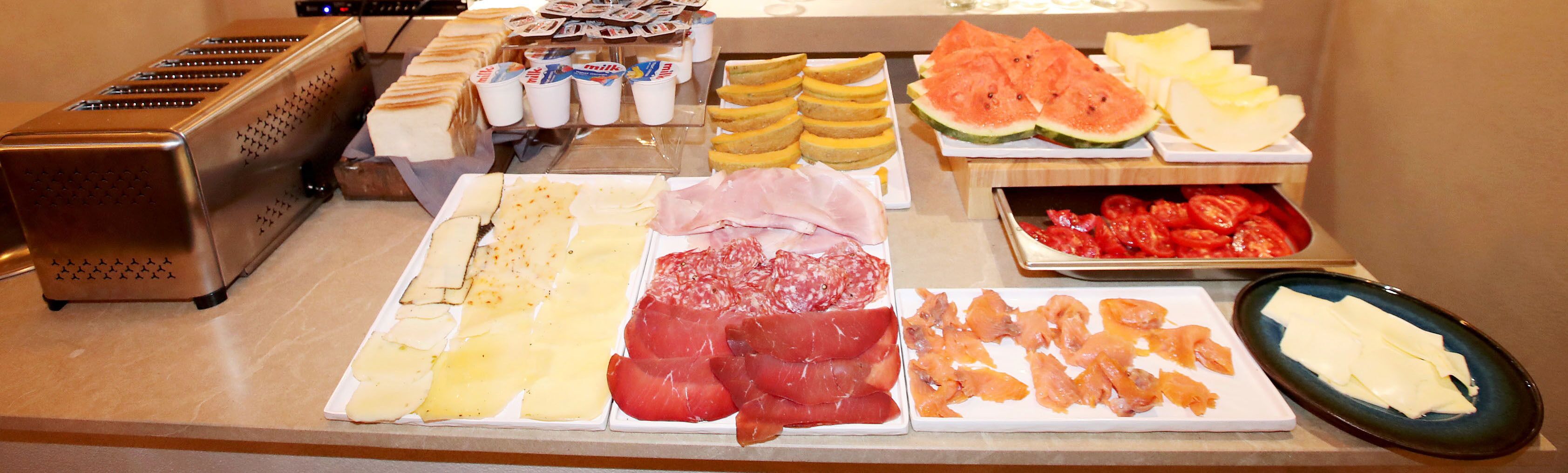 A buffet with various food items including cheese, meats, and fruits.