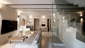 Een moderne woonkamer met een grote flatscreen televisie, een bank, een salontafel en een glazen scheidingswand.