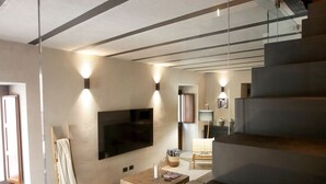 Een moderne woonkamer met een flatscreen-tv, een bank en een trap.