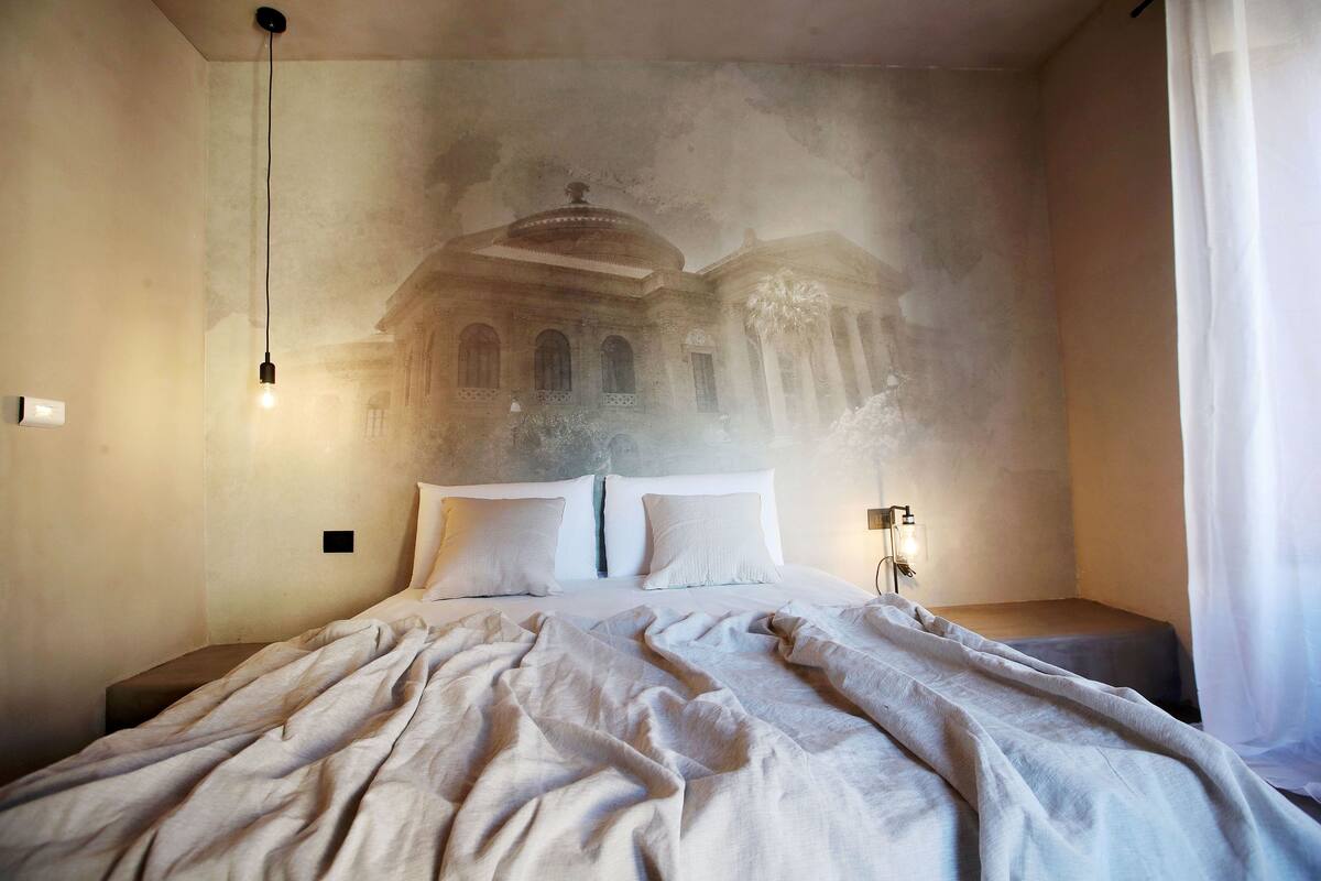 Ein Schlafzimmer mit Bett, Nachttisch, Wandlampe und Deckenleuchte.