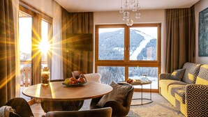 Een moderne woonkamer met een houten eettafel, een bank en uitzicht op een besneeuwde berg.