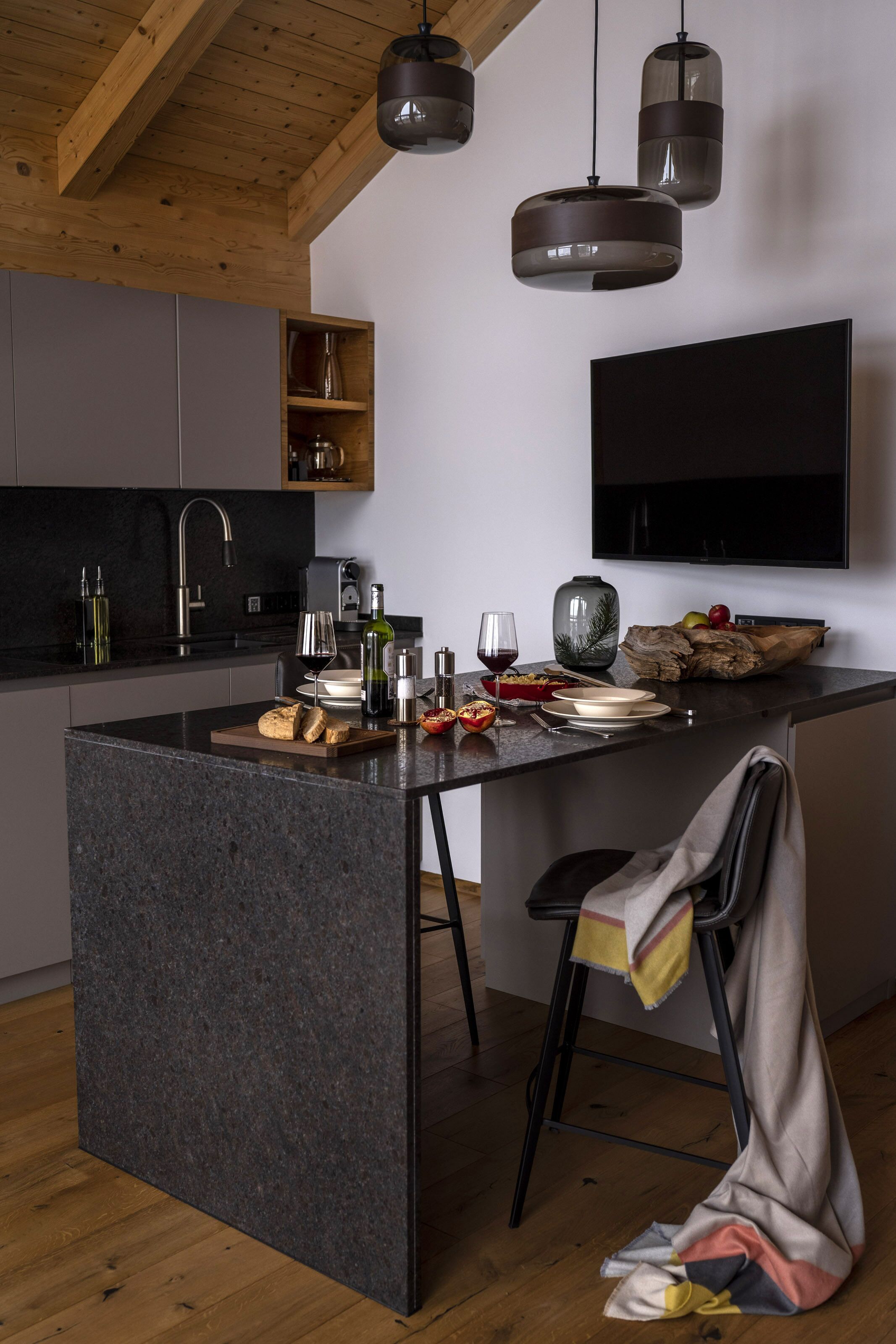 A modern kitchen with a central island, built-in appliances, and pendant lighting.