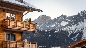 Een houten hut met een balkon met uitzicht op besneeuwde bergen.