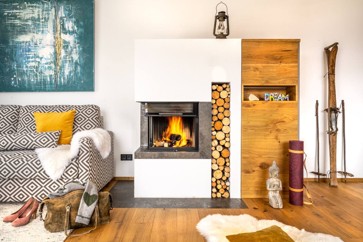 Una sala de estar con chimenea, un sofá con cojines estampados, una estatua decorativa de Buda y una colchoneta para yoga.