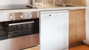 A compact kitchen with wooden cabinets, a microwave, a coffee maker, a sink, and a dishwasher. - VVF Résidence Plagne 1800 Paradiski (La Plagne-Tarentaise)