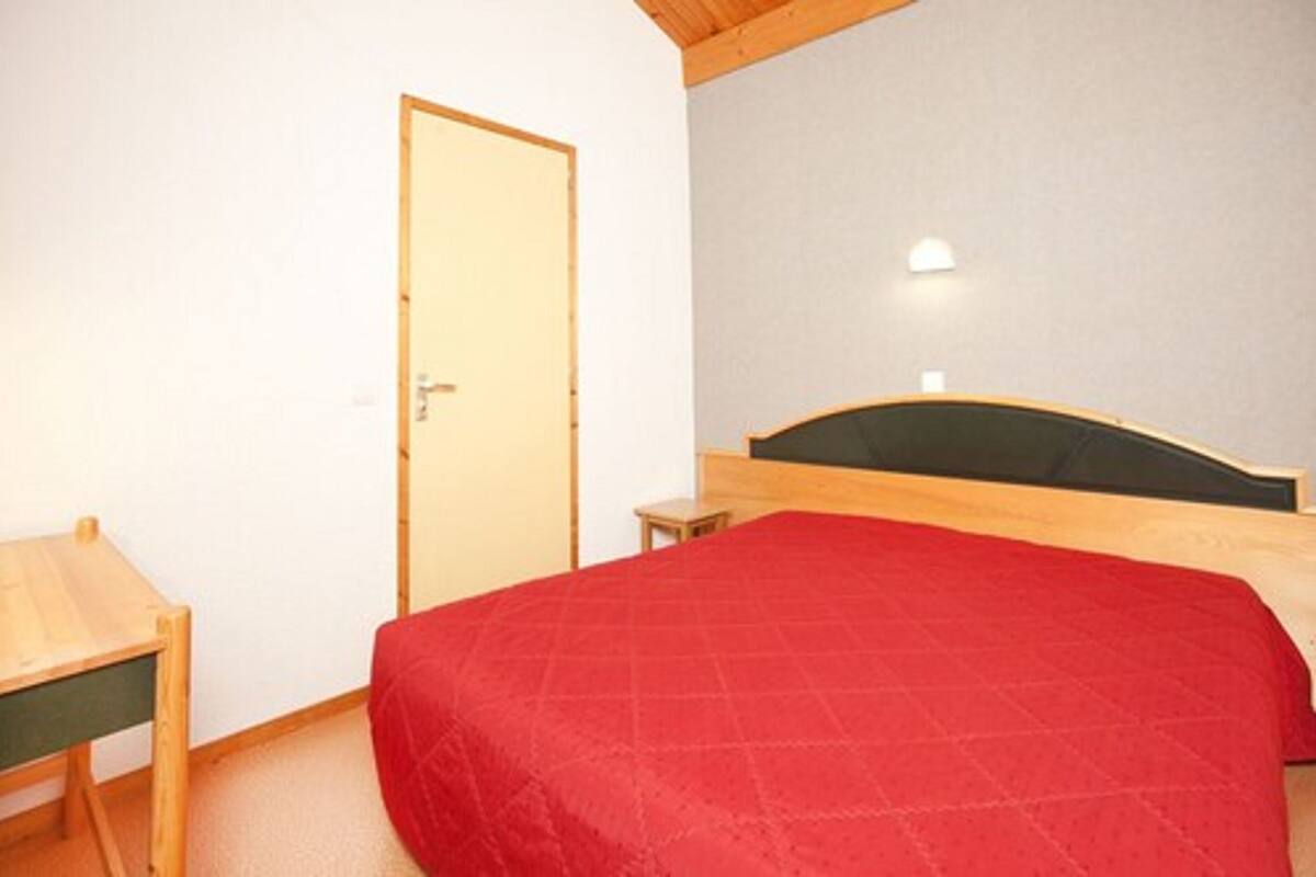 Un dormitorio con una cama, una mesita y una puerta.