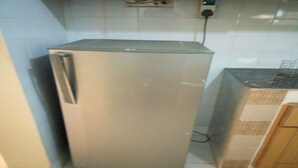 Ein kompakter, edelstahlfarbener Kühlschrank in einer Küche mit gefliesten Wänden und einem gefliesten Boden.