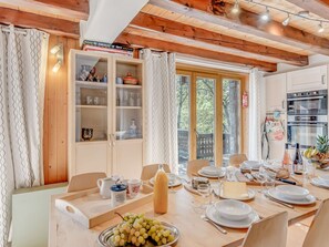 A dining area with a wooden table set for a meal, a cabinet with glass doors, and a view through large windows. - Family chalet for 14, 7 bedrooms, terrace, wifi included (Champagny-en-Vanoise)