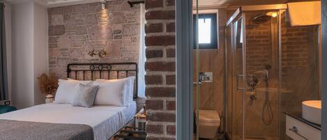Un dormitorio con cama, mesita de noche, pared de ladrillo y ducha con mampara de vidrio.