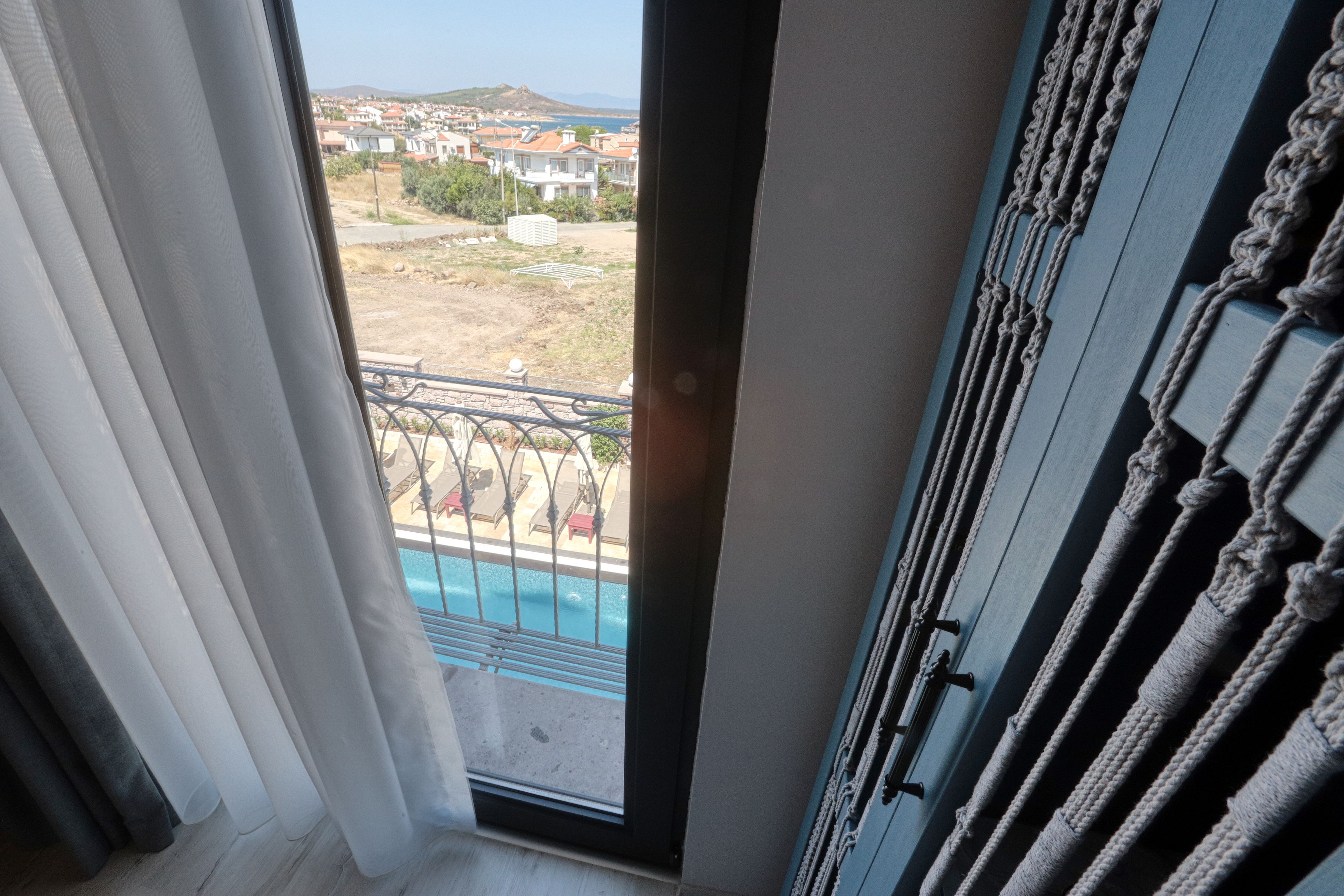 A view from a balcony with a pool, a clear sky, and distant buildings.