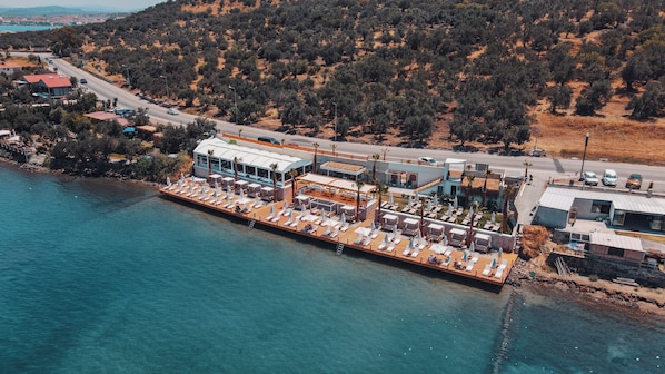 An aerial view of a waterfront property with a dock, lounge area, and buildings.