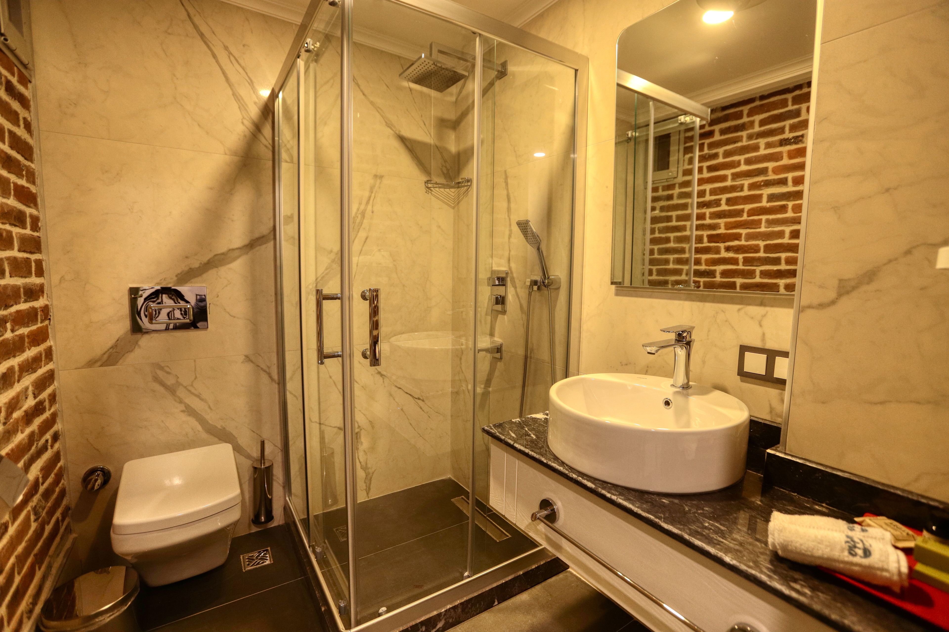 A modern bathroom with a glass-enclosed shower, a white sink, and a toilet.