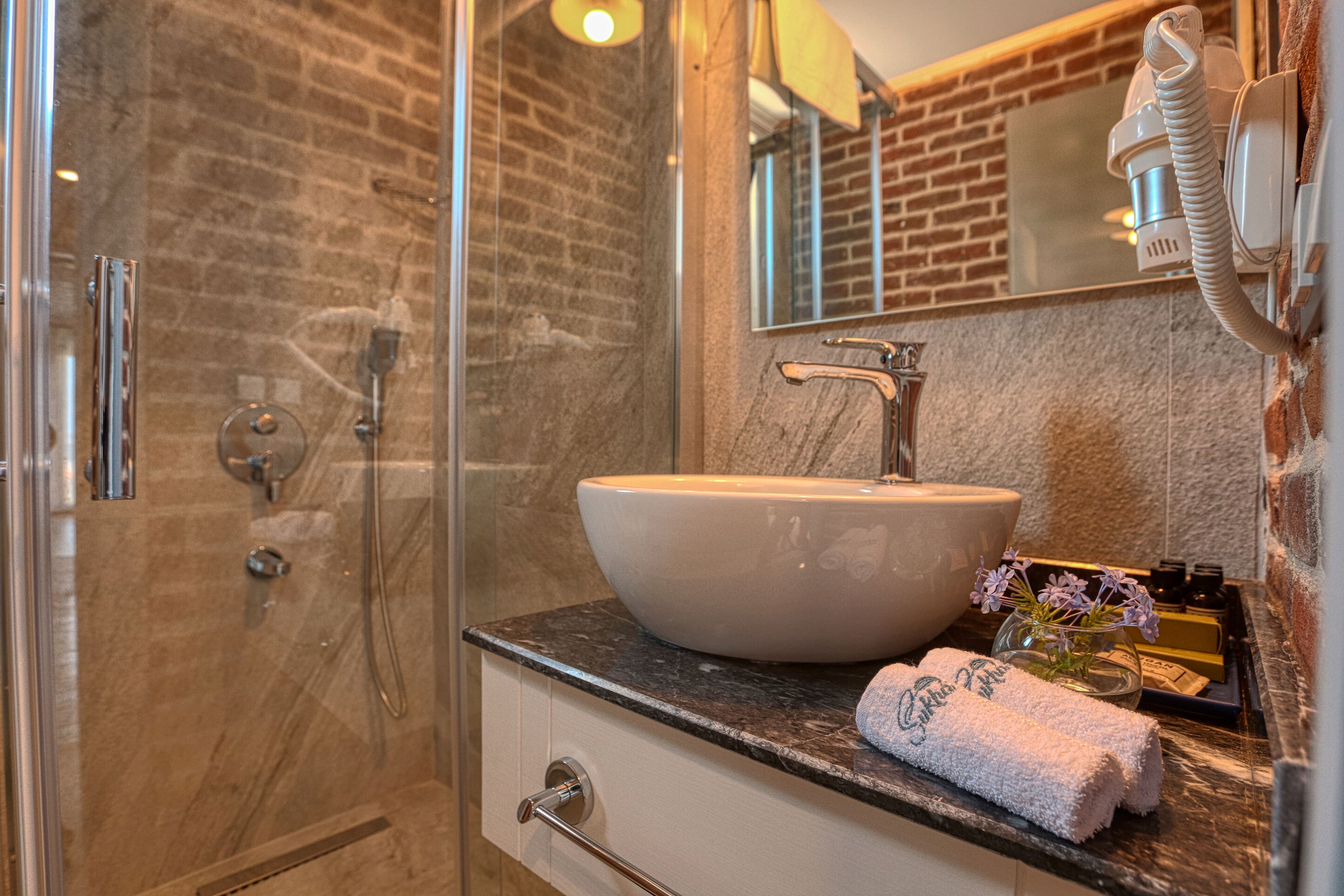A bathroom with a glass-enclosed shower, a white sink, and a mirror above it.