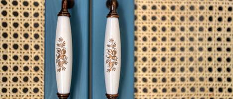 Two white door handles with brown accents and floral designs, mounted on a blue door.