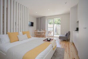 A modern hotel room with a large bed, a dining area, and a seating space. - Liiiving in Porto - Charming Downtown Delight I (Porto)