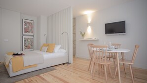 Ein modernes Schlafzimmer mit Bett, Nachttisch und einem Essbereich mit Stühlen und Tisch.
