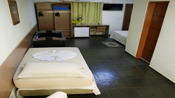 Habitación de hotel compacta con una cama individual, un escritorio pequeño, una silla y un armario.