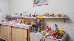 Una barra de desayuno con diversos alimentos y bebidas, como frutas, una cafetera y condimentos.