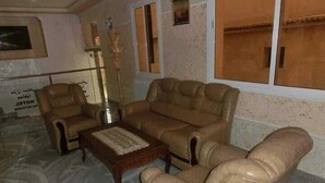 A living room with a sofa set, a coffee table, and a decorative vase. - Hotel Djhaltia (Ténès)