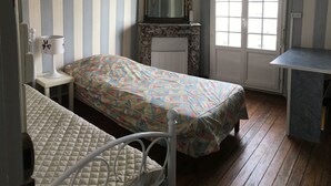 Une pièce avec un lit, une petite table, un miroir et une fenêtre.