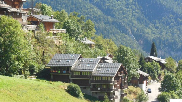 A hillside chalet with multiple balconies, surrounded by lush greenery and mountains. - Champagny-en-Vanoise: 5-room apartment, 8 pers, pets allowed (Champagny-en-Vanoise)