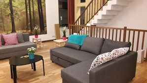 A modern living room with a grey sofa, a coffee table, and a staircase. - Chez Esmara Et Philippe Maisonette (Brussels)